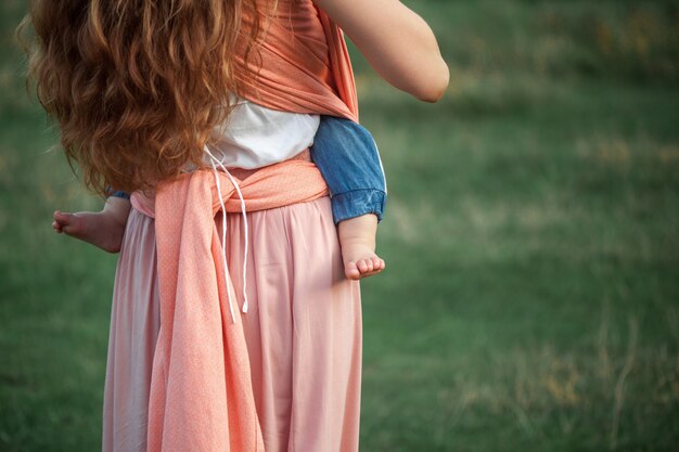 Young beautiful mother hugging her little toddler son outdoors