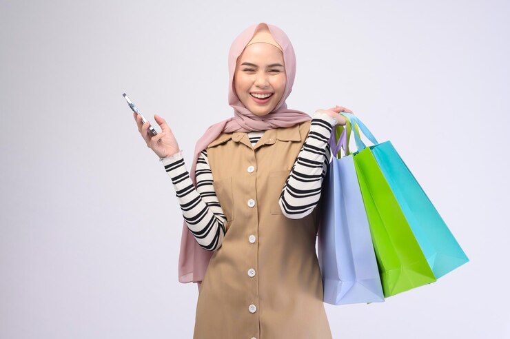  A young beautiful muslim woman in suit holding colorful shopping bags over white background studio 