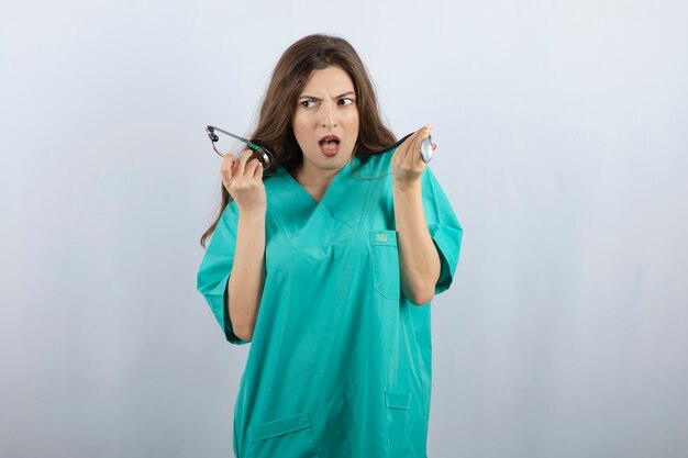 Young beautiful nurse in green uniform holding stethoscope 