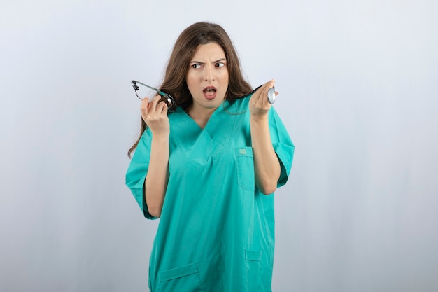 Young beautiful nurse in green uniform holding stethoscope 