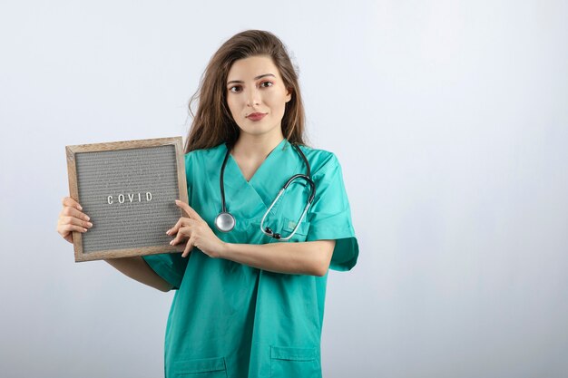 フレームを保持している聴診器と緑の制服を着た若い美しい看護師