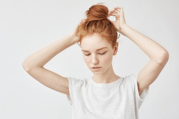 Young beautiful redhead woman correcting hair bun.