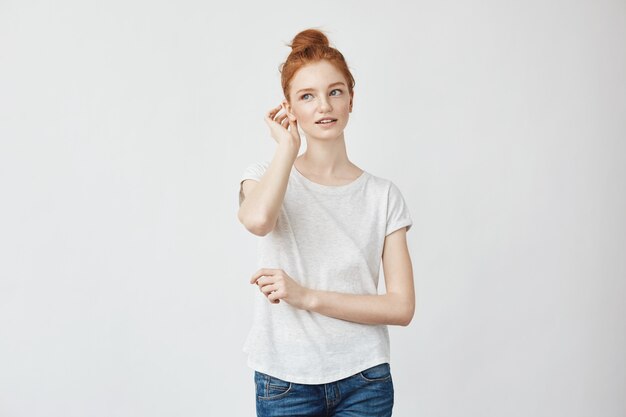 Young beautiful redhead woman smiling correcting hair.