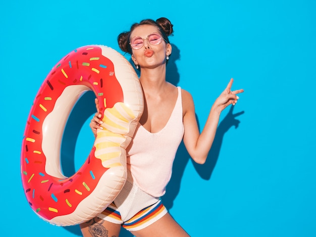 Young beautiful sexy smiling hipster woman in sunglasses. with donut lilo inflatable mattress..Shows peace sign