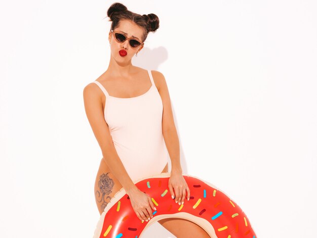 Young beautiful sexy smiling hipster woman with red lips in sunglasses with donut lilo inflatable mattress.