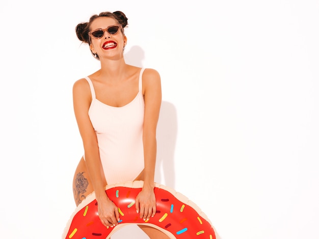 Young beautiful sexy smiling hipster woman with red lips in sunglasses with donut lilo inflatable mattress