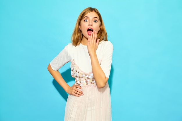 Young beautiful shocked woman . Trendy woman in casual summer clothes.  Funny model isolated on blue wall