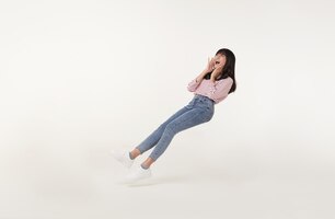 Free photo young beautiful smiling asian girl floating in midair shout story and announcement something