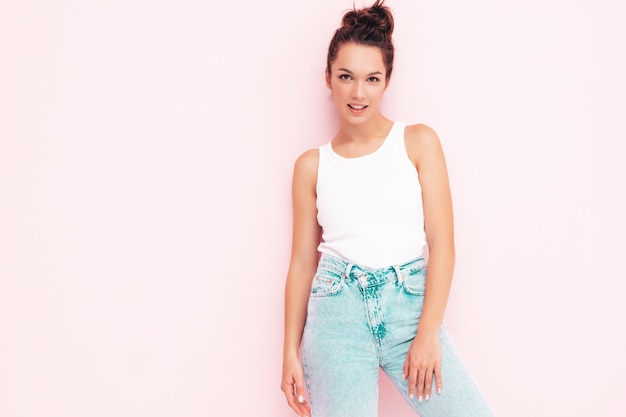 Young beautiful smiling female in trendy summer clothes carefree woman posing near wall in studio Positive brunette model having fun Cheerful and happy