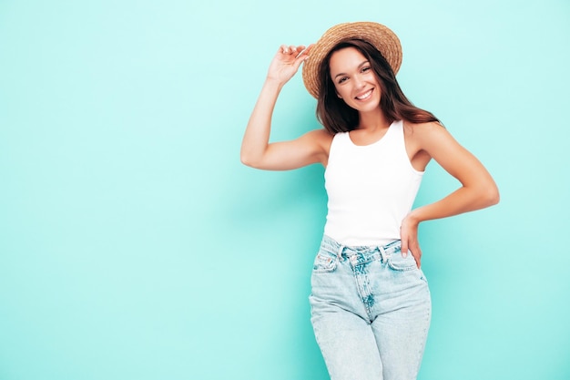 최신 유행의 여름 옷을 입은 젊고 아름다운 웃는 여성 스튜디오의 파란색 벽 근처에서 포즈를 취하는 섹시한 평온한 여자 긍정적인 갈색 머리 모델 재미 명랑하고 행복한 모자