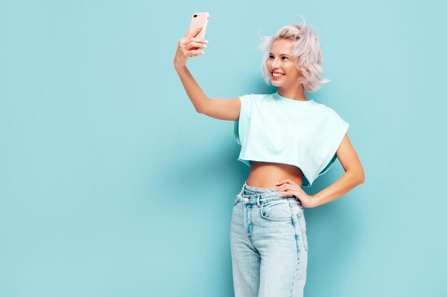 Young beautiful smiling female in trendy summer clothes Sexy carefree woman posing near in studio Positive blond model having fun and going crazy Cheerful and happy