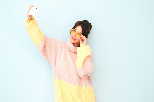 Young beautiful smiling female in trendy summer colorful sweater