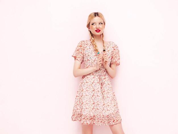 Young beautiful smiling female in trendy summer dress sexy carefree blond woman posing near wall in studio model having fun cheerful and happy