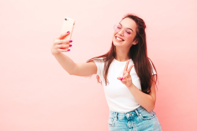 Young beautiful smiling female in trendy summer hipster clothes