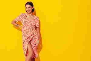 Free photo young beautiful smiling female in trendy summer red dress sexy carefree woman posing near yellow wall in studio positive model having fun cheerful and happy isolated