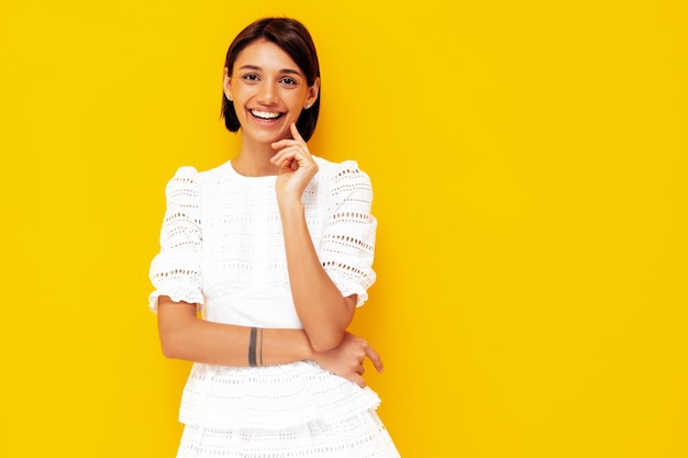 Young beautiful smiling female in trendy summer white dress Sexy carefree woman posing near yellow wall in studio Positive model having fun Cheerful and happy Isolated