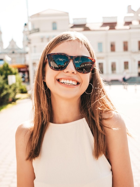 Young beautiful smiling hipster woman in trendy summer clothes Sexy carefree woman posing on the street background at sunset Positive model outdoors Cheerful and happy in sunglasses