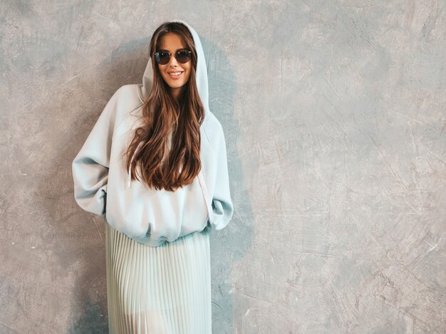 Young beautiful smiling woman looking . Trendy girl in casual summer hoodie and skirt clothes.  