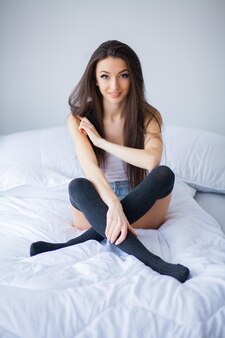 Young beautiful smiling woman waking up at white bedroom