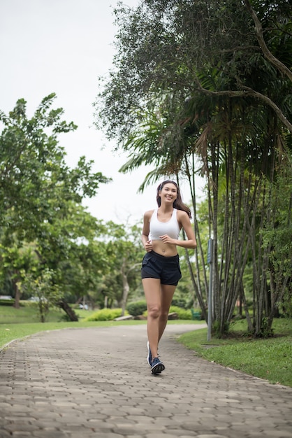 公園で走っている若い美しいスポーツの女性。健康とスポーツのコンセプト。