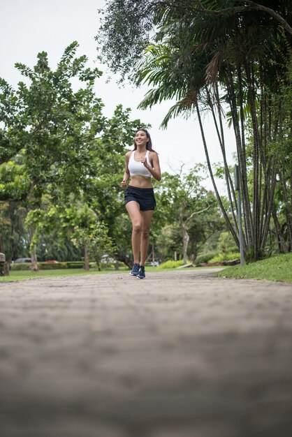 公園で走っている若い美しいスポーツの女性。健康とスポーツのコンセプト。