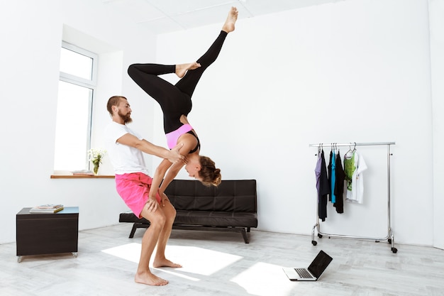 Young beautiful sportive couple training yoga asanas at home.