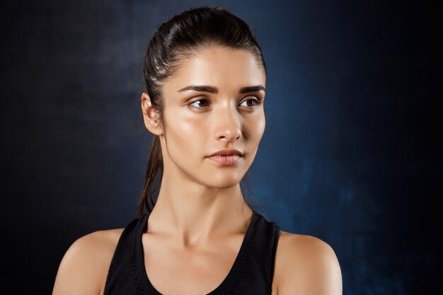  young beautiful sportive girl posing over dark wall.