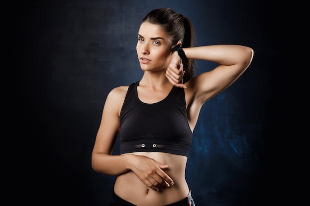  young beautiful sportive girl posing over dark wall.