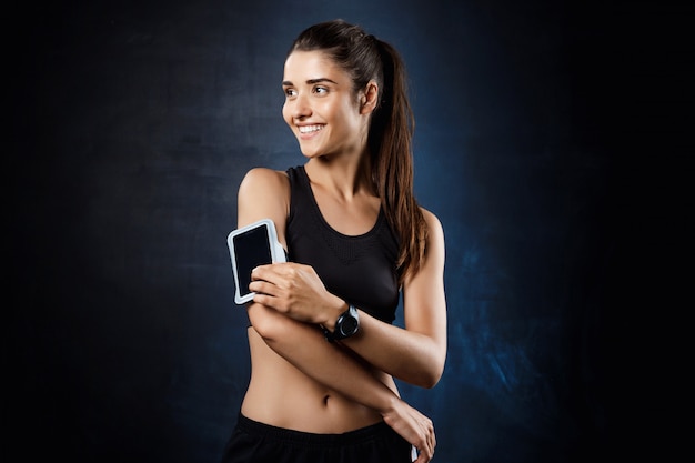 Young beautiful sportive girl posing over dark wall.