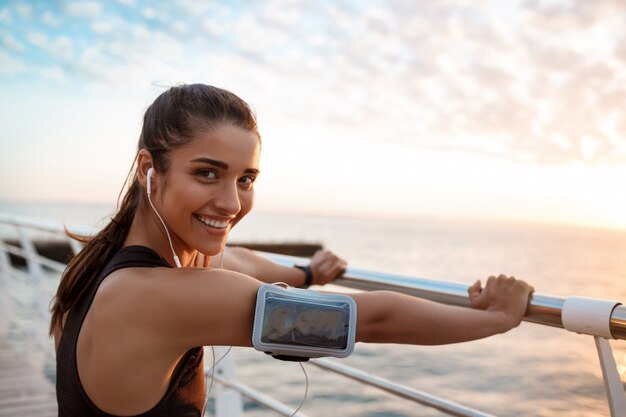 Young beautiful sportive girl training at sunrise over seaside.