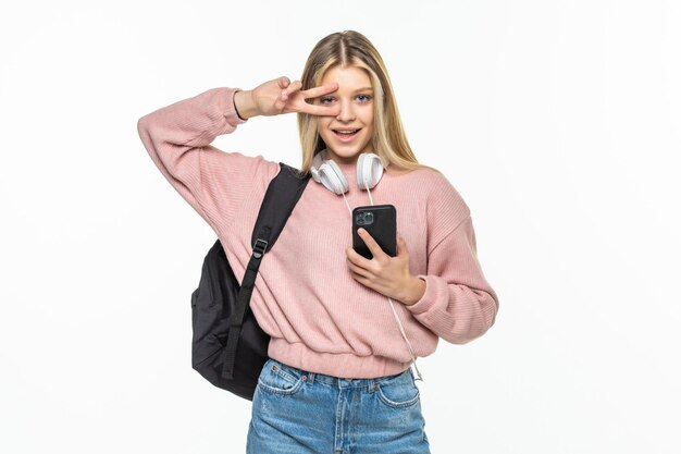 Young beautiful student woman with backpack makes selfie isolated on white wall in studio