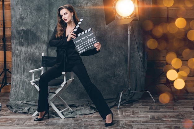 Free photo young beautiful stylish sexy woman on cinema backstage, holding movie clapper