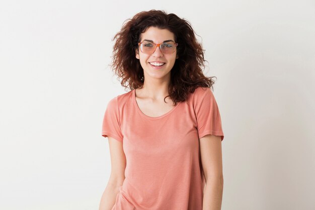 Young beautiful stylish woman in glasses, curly hair, sincere smiling, positive emotion, happy, isolated, pink t-shirt