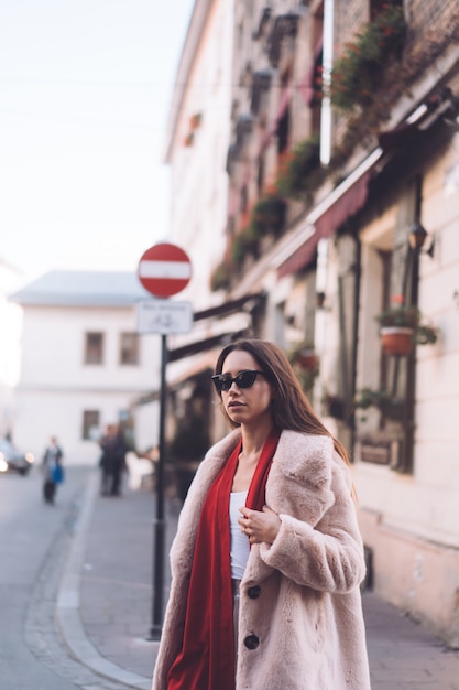 Young beautiful stylish woman walking in pink coat