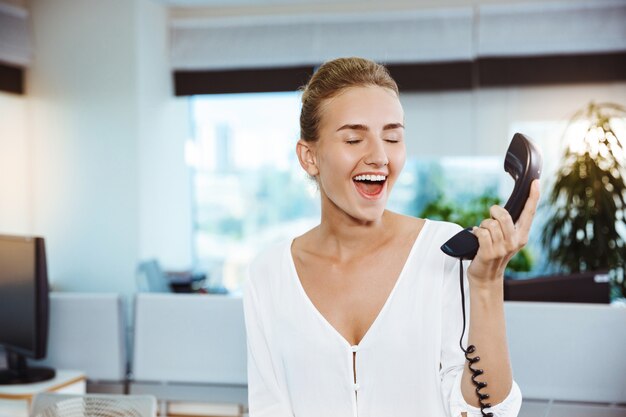 Young beautiful successful businesswoman smiling, speaking on phone, over office