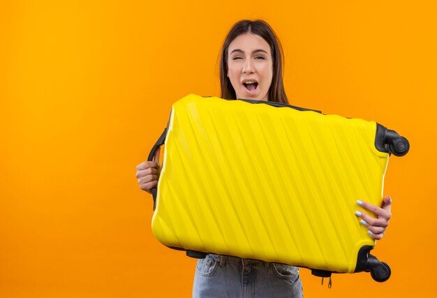 Young beautiful traveler girl holding suitcase looking at camera confused