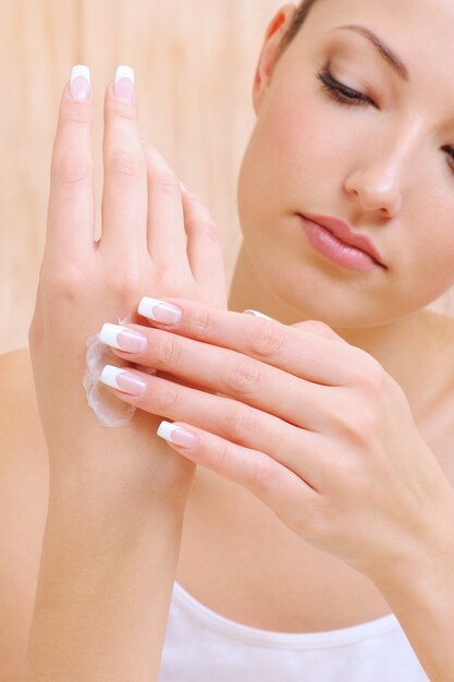 Young beautiful Woman applying cosmetic cream on hands