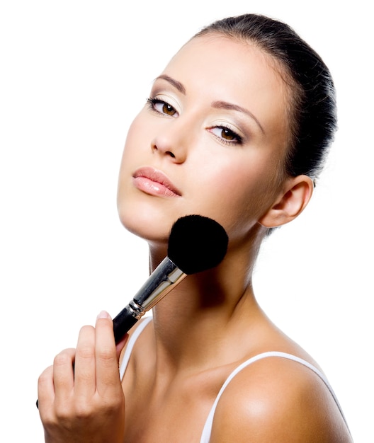 Free photo young beautiful woman applying powder on cheekbone with brush - isolated
