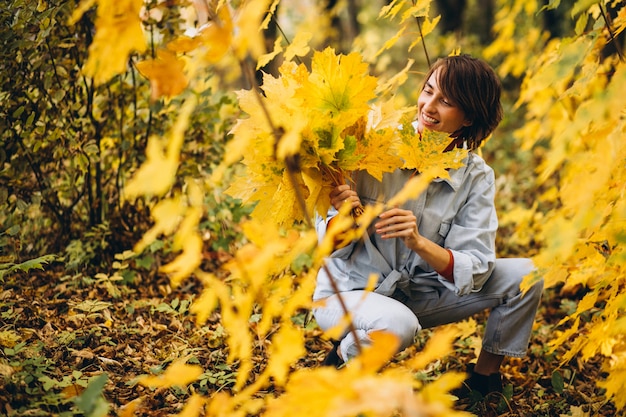Молодая красивая женщина в осеннем парке, полном листьев