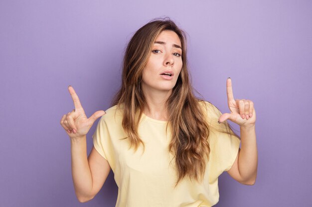 Young beautiful woman in beige t-shirt looking at camera with confident expression