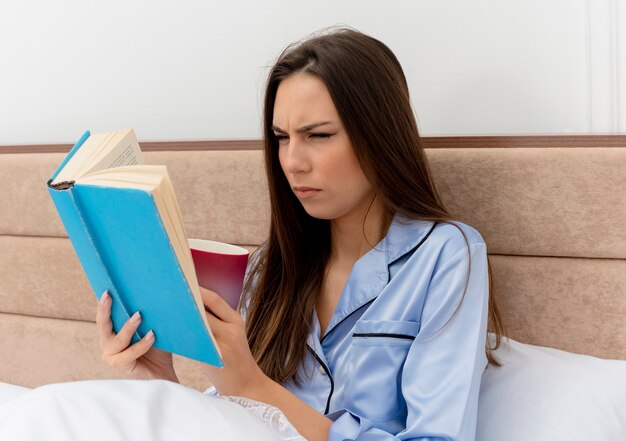 Young beautiful woman in blue pajamas laying on bed