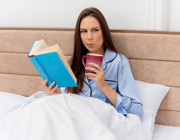 ベッドに横たわっている青いパジャマの若い美しい女性