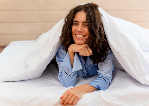 Young beautiful woman in blue pajamas laying on bed