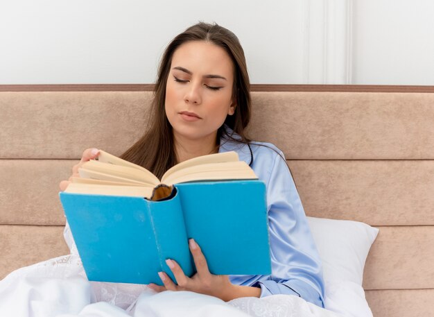 Young beautiful woman in blue pajamas laying on bed