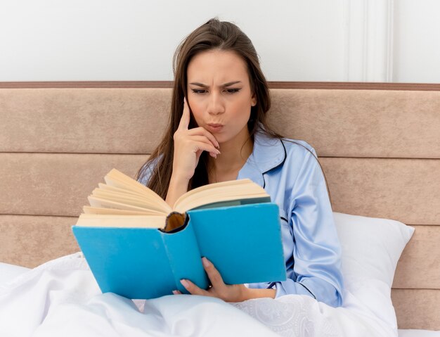 Young beautiful woman in blue pajamas laying on bed