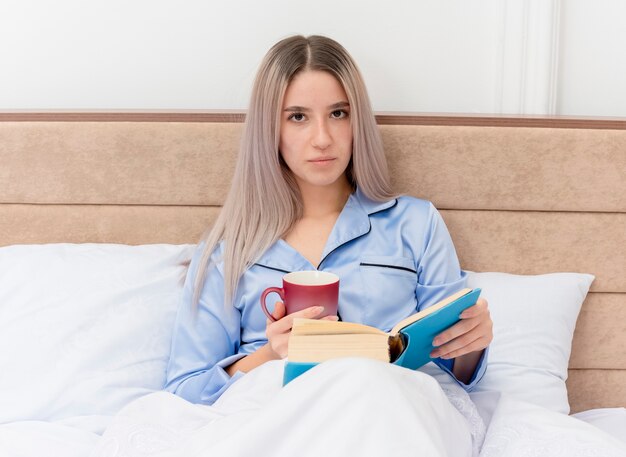 Young beautiful woman in blue pajamas laying on bed