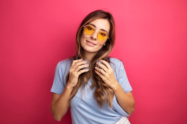 Young beautiful woman in blue t-shirt wearing yellow glasses