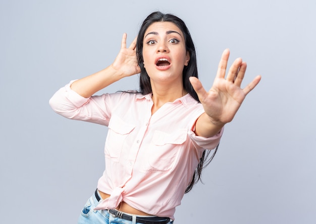 Young beautiful woman in casual clothes  worried and confused making stop gesture with hand standing over white wall