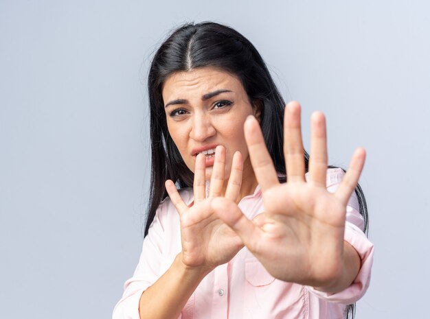 Young beautiful woman in casual clothes  worried making stop gesture with hands standing over white wall