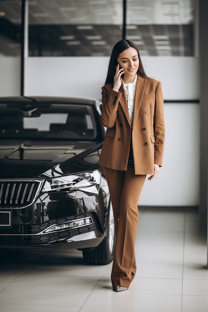 Young beautiful woman choosing car in a car showroom